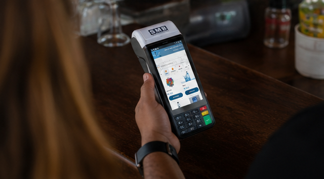 Operadora usando maquininha SMB Empresa em atendimento no bar